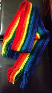 A folded scarf in long, crocheted, rainbow stripes.